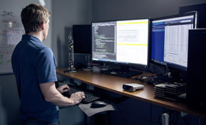 A tech worker uses a dual screen PC workstation.
