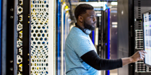 Image of a man in a datacenter tapping on a computer screen.