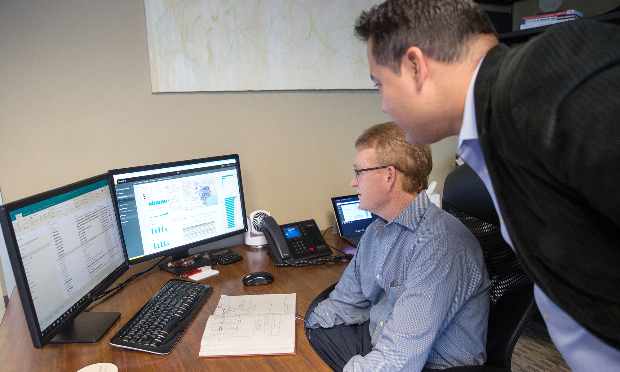 Image of two coworkers looking at computer monitors.