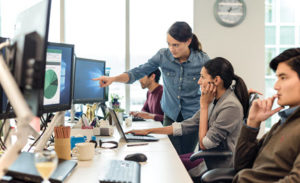 Image of coworkers pointing at a computer monitor.