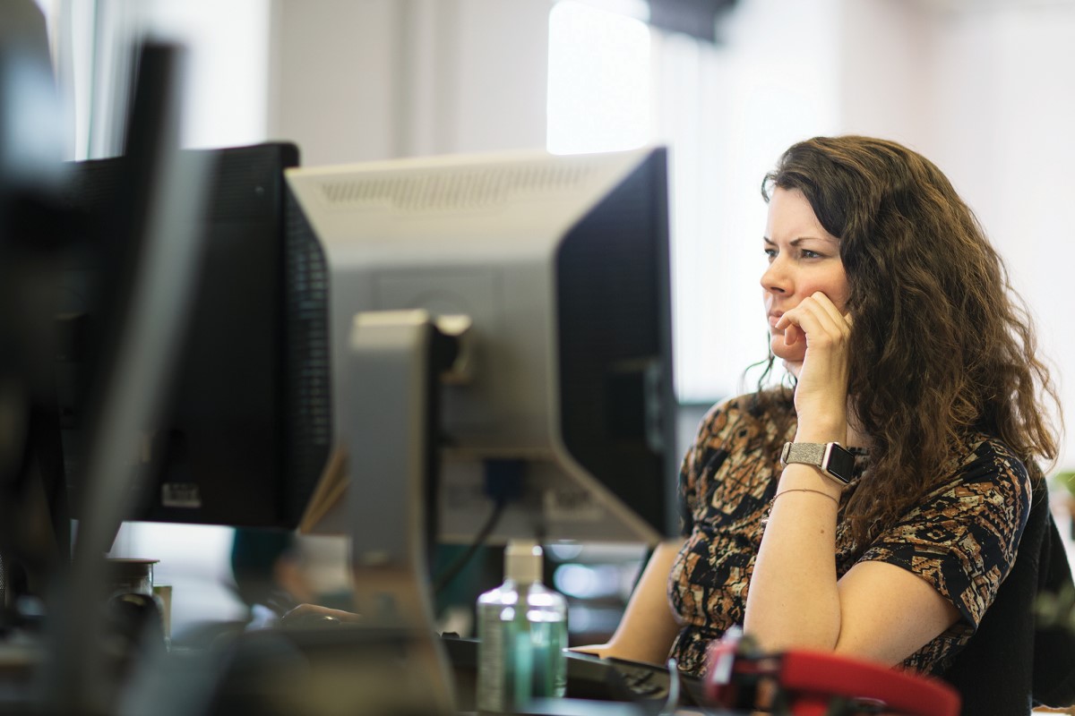 Adult woman sitting behind a computer screen.