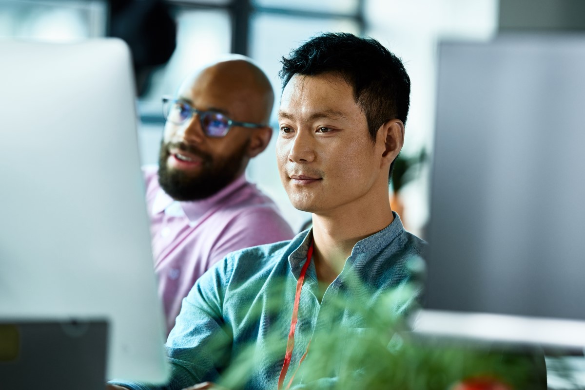 Two male co-workers looking at computer screen and concentrating.