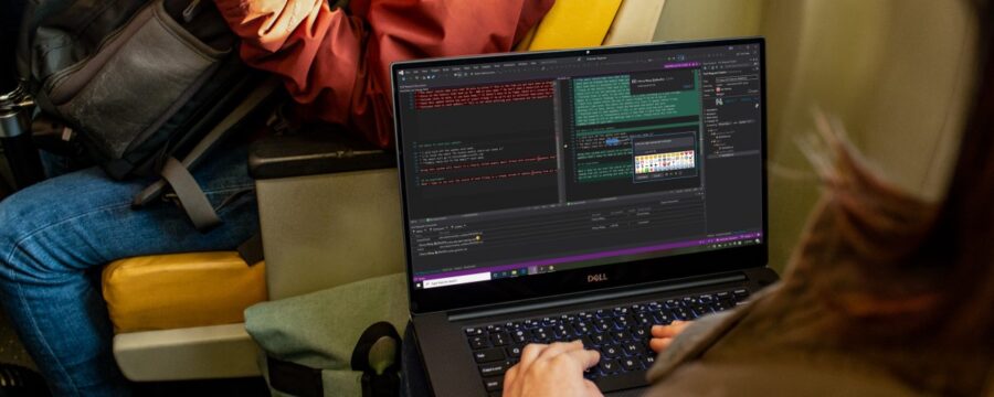 Developer coding on PC laptop during commute in public transport.