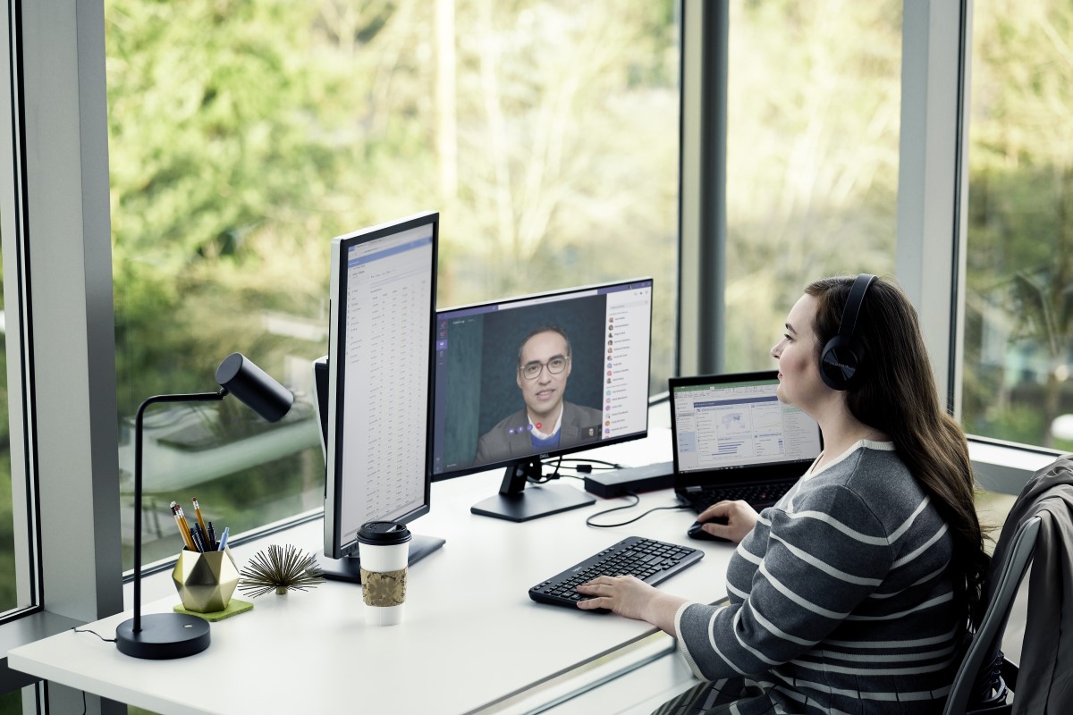 Adult female working from home using multiple desktop screens.
