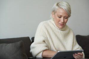 Woman using a credit card to place a secure online order via her tablet while sitting on her couch at home.