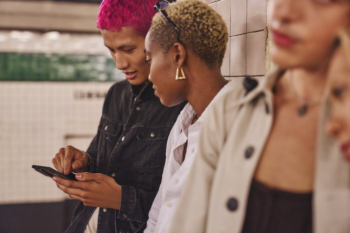 Two people in the subway looking at a mobile device.