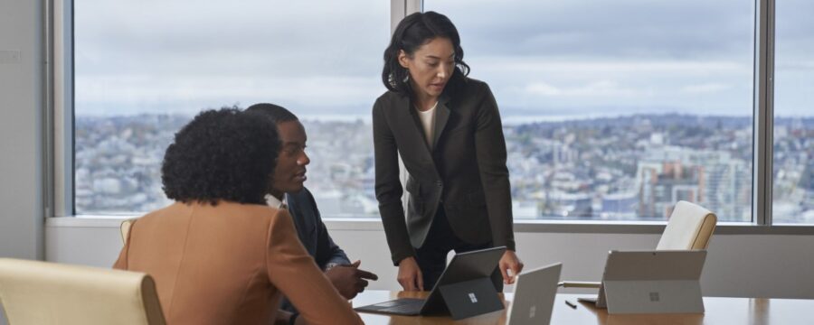 Conference room table with four people in a meeting with Surface Laptop Go 2 and Surface 2-in-1‘s.