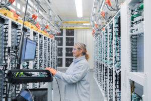 Female datacenter employee performs maintenance in datacenter cold aisle.