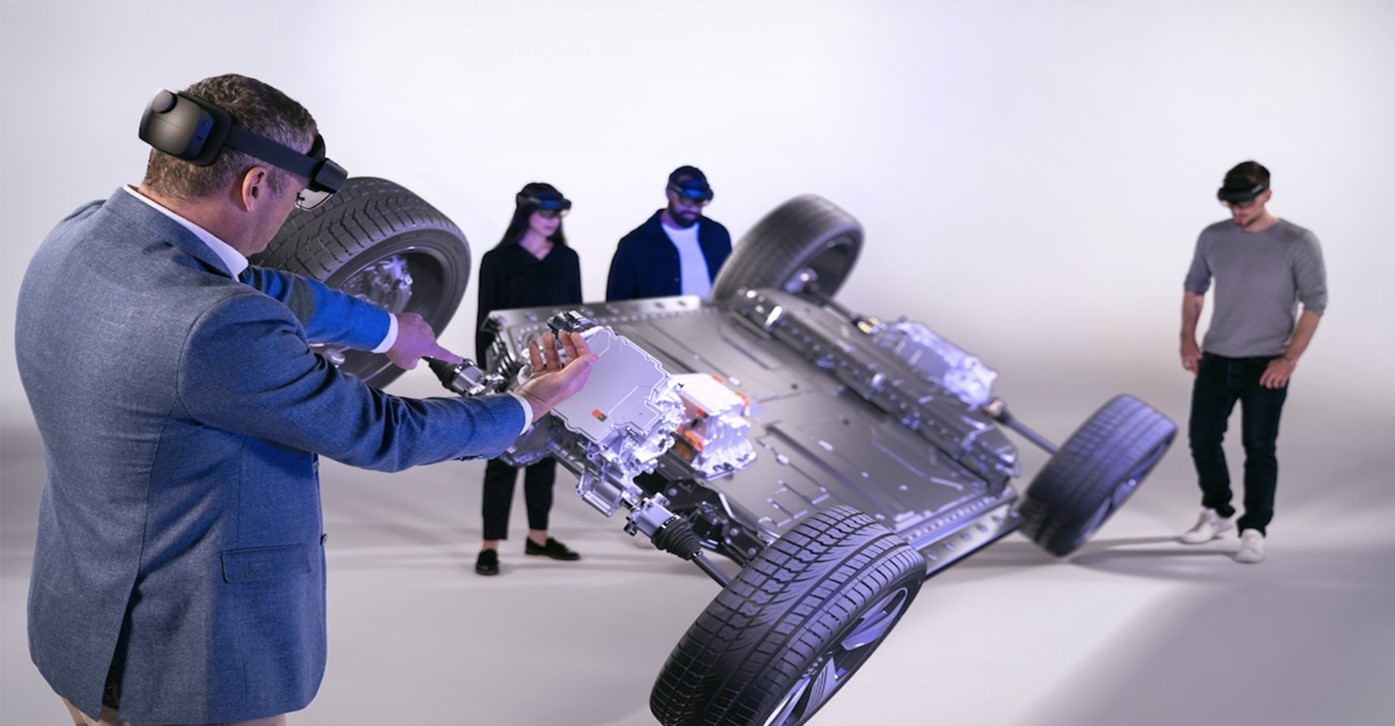 Group of people wearing Microsoft Hololens headsets viewing a VR image of a four-wheel vehicle chassis.