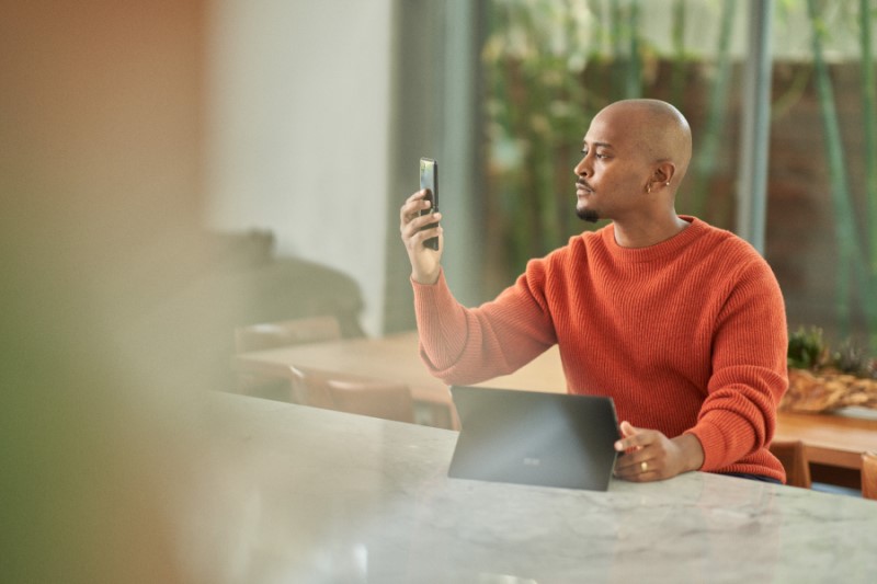 Seller completing multi-factor authentication via facial recognition on a mobile phone before working from home.