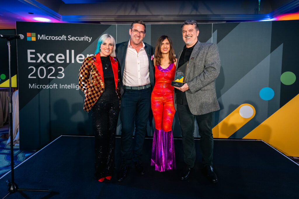 4 people posing with a trophy at an awards ceremony.