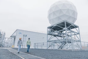 Photo of Orbital Ground Station satellite uplink. Two male datacenter employees walk side by side beneath the orbital ground station