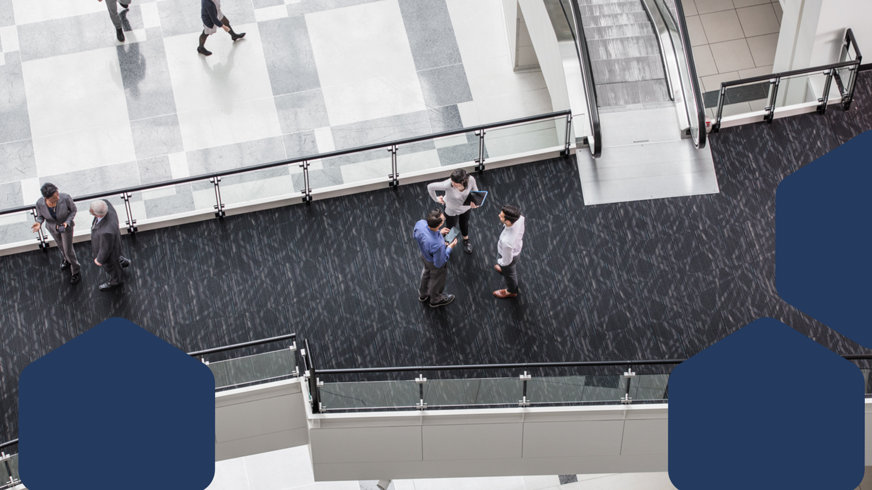 A group of people standing on a floor of a building lobby discussing