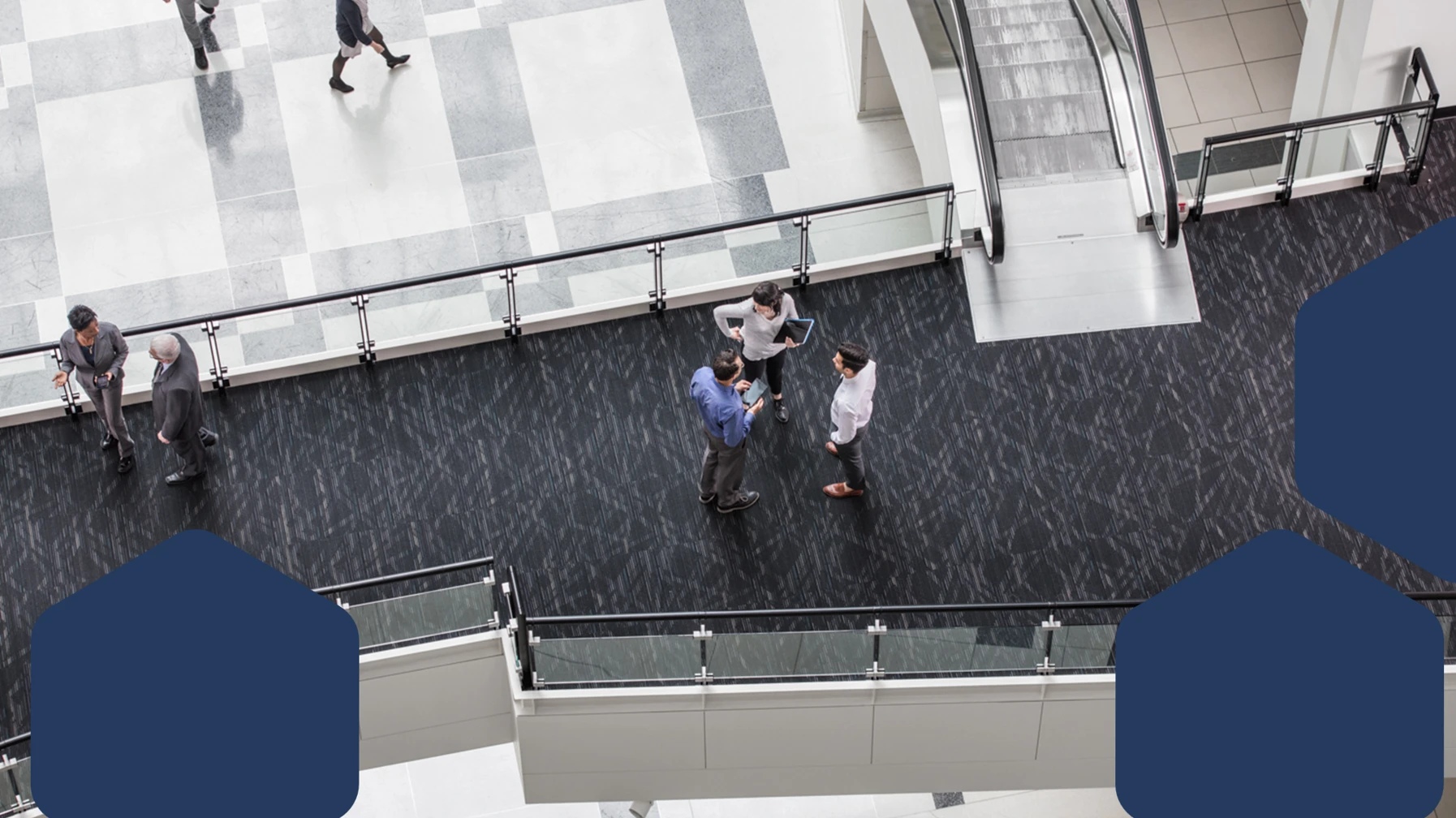 A group of people standing on a floor of a building lobby discussing