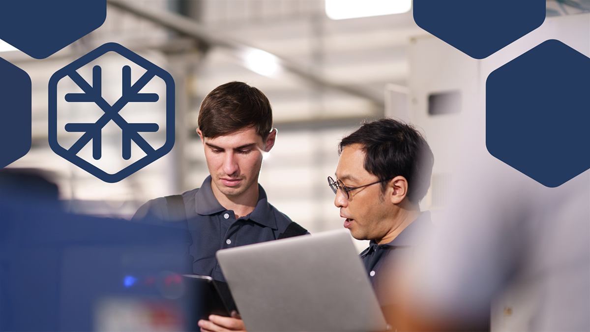 Photo of IT support specialists looking at a laptop, with blue hexagon overlay