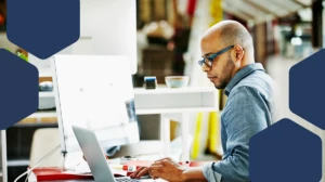 Photo of businessman sitting at workstation in startup office working on project on laptop