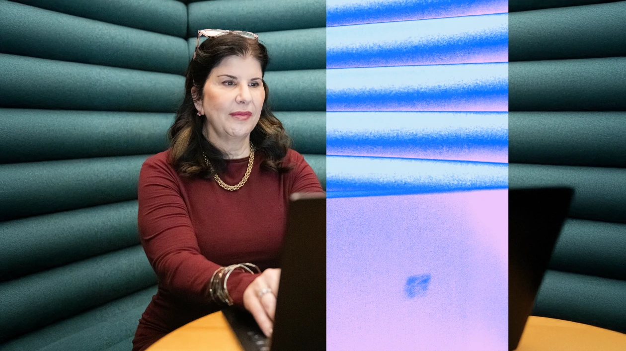 Woman sitting at laptop with red long sleeve and gold chain on