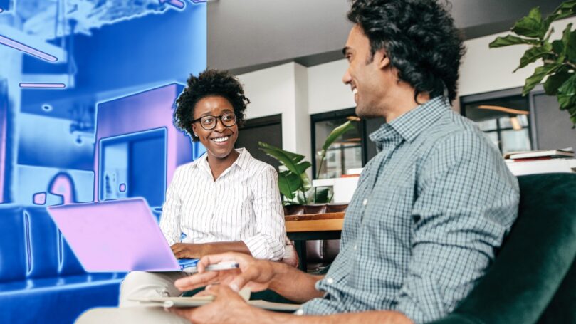 Two people on a security team sit at laptops together.