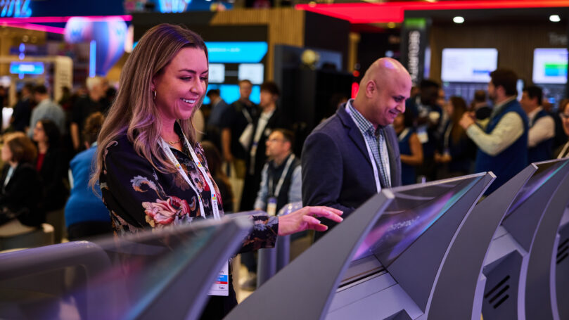 People interacting with touch screen at conference.