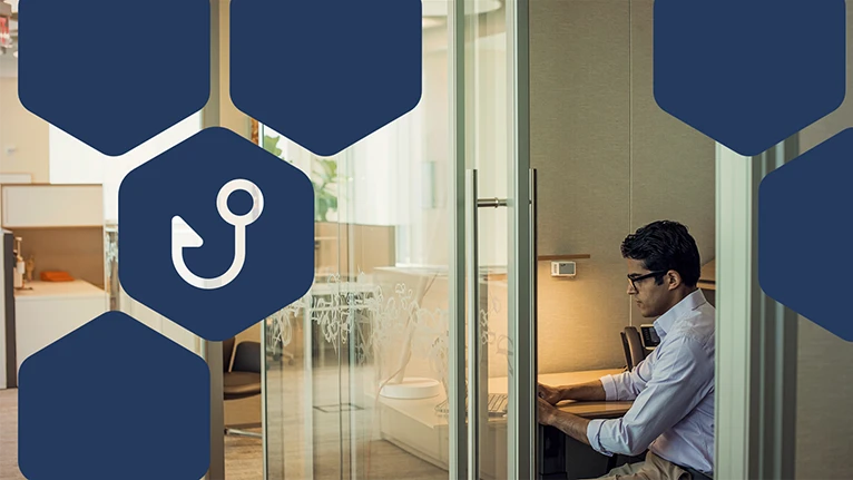 Photo of man in office using laptop, with blue hexagon overlays and the icon for phishing