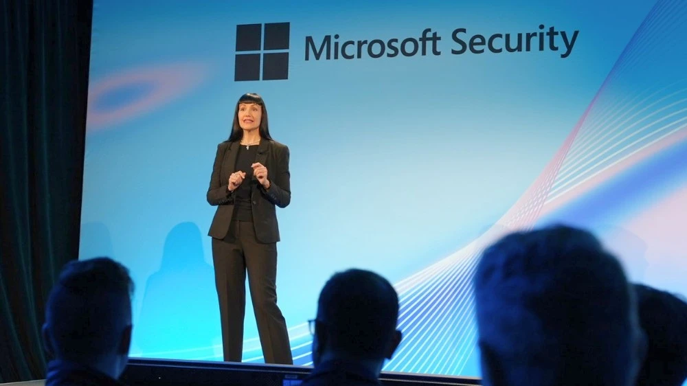 Woman speaking at a conference in front of a microsoft security projection
