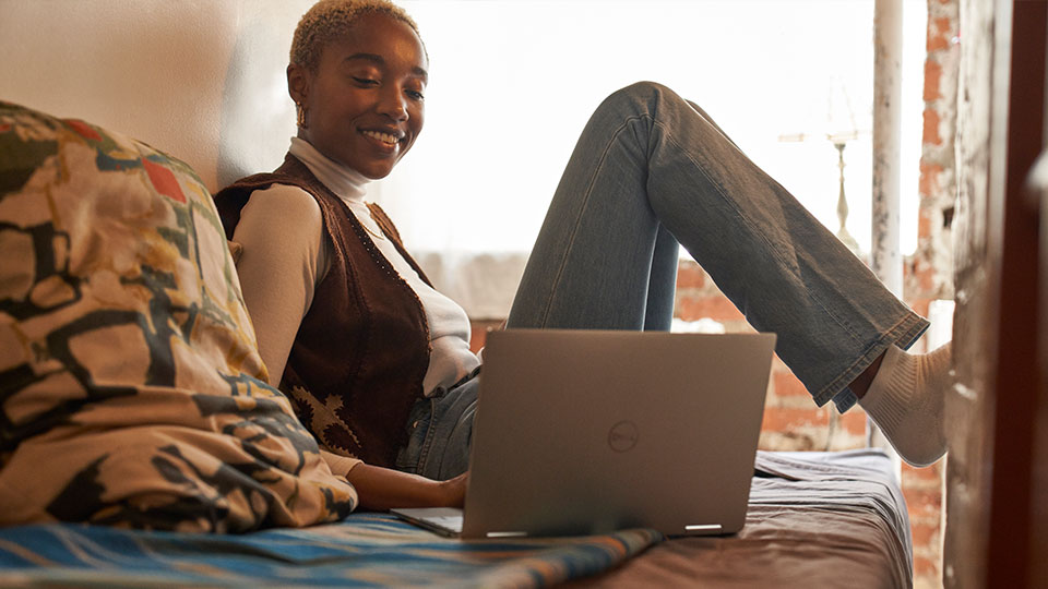A woman reclines comfortably typing on a laptop