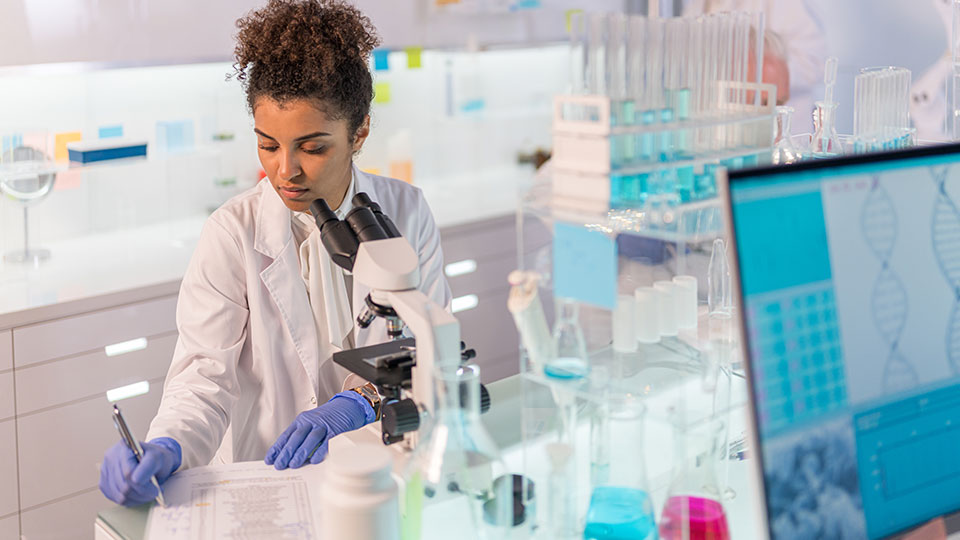 A scientist records results on a document in a lab