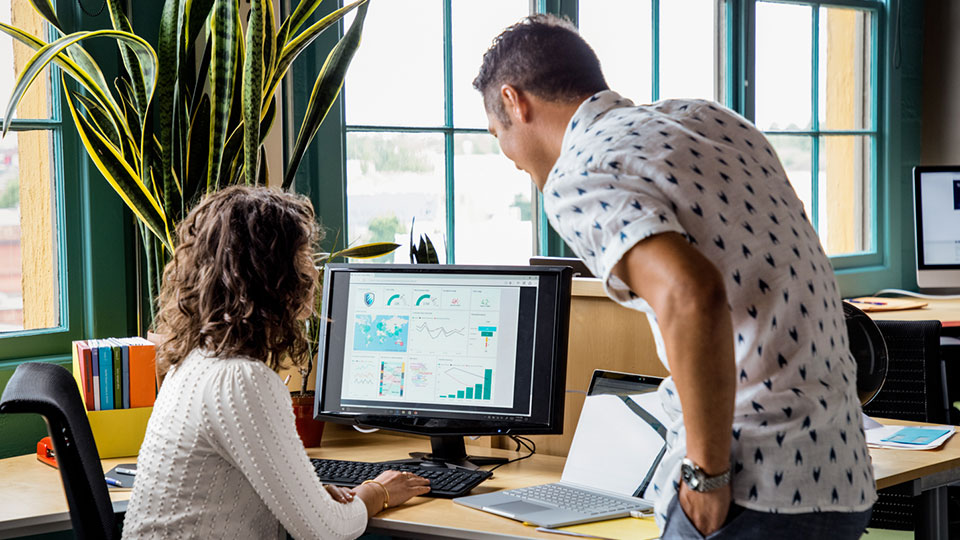 A pair of coworkers read data on a computer monitor