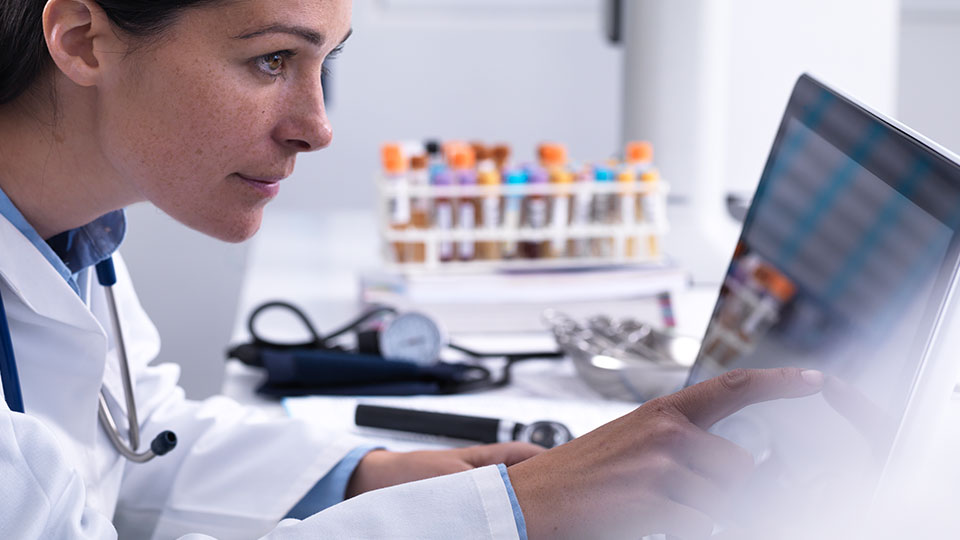 A medical professional consults a laptop in a lab