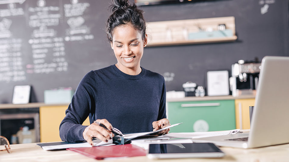 A woman in an office environment prepares a presentation folder