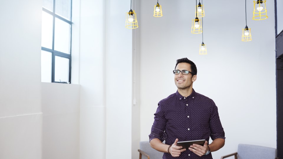 Man holding tablet with lightbulbs over his head