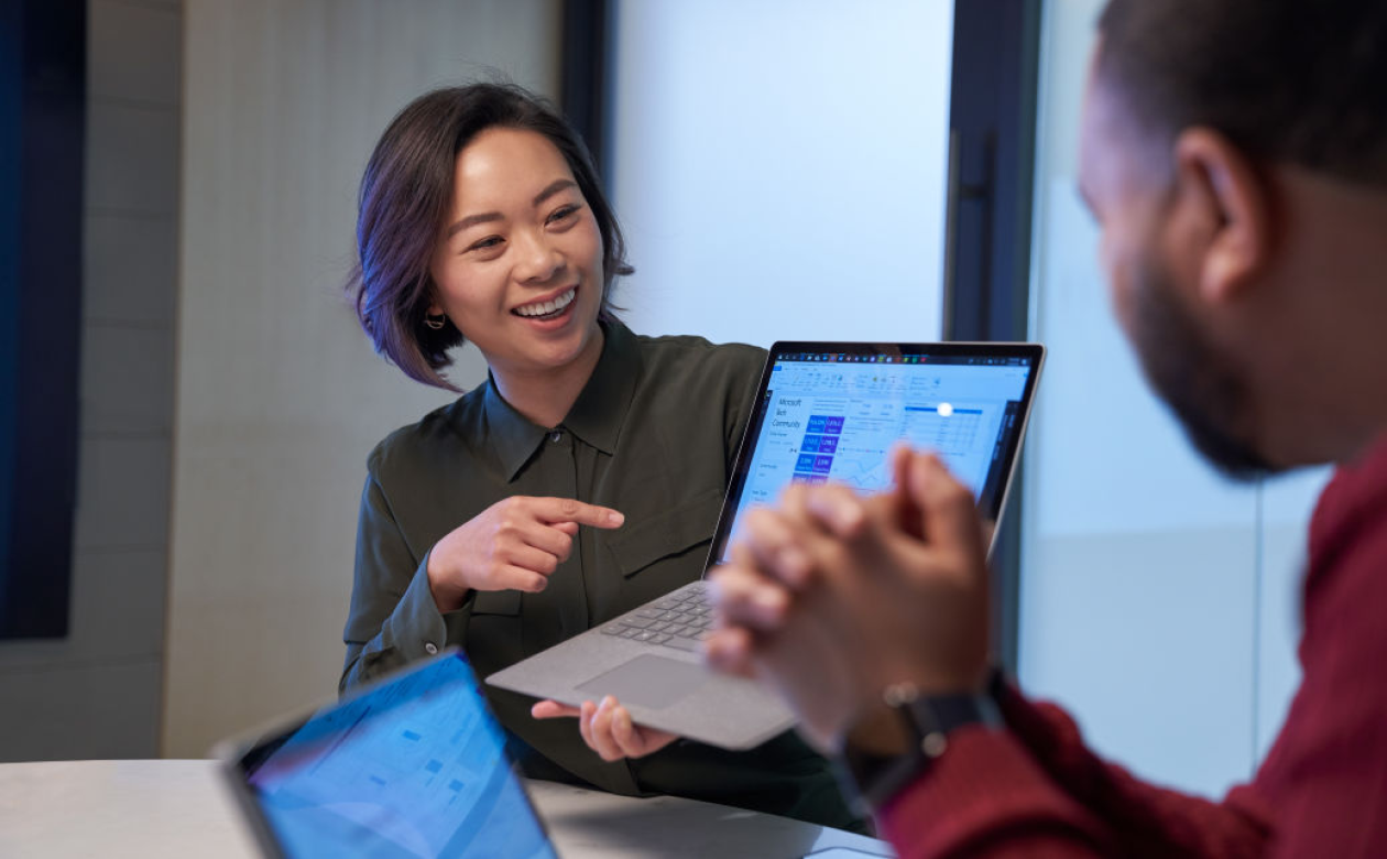 A woman shows a colleague a view of her computer screen.
