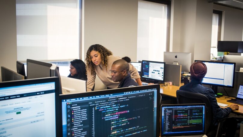 A team of workers sit at their computers collaborating.