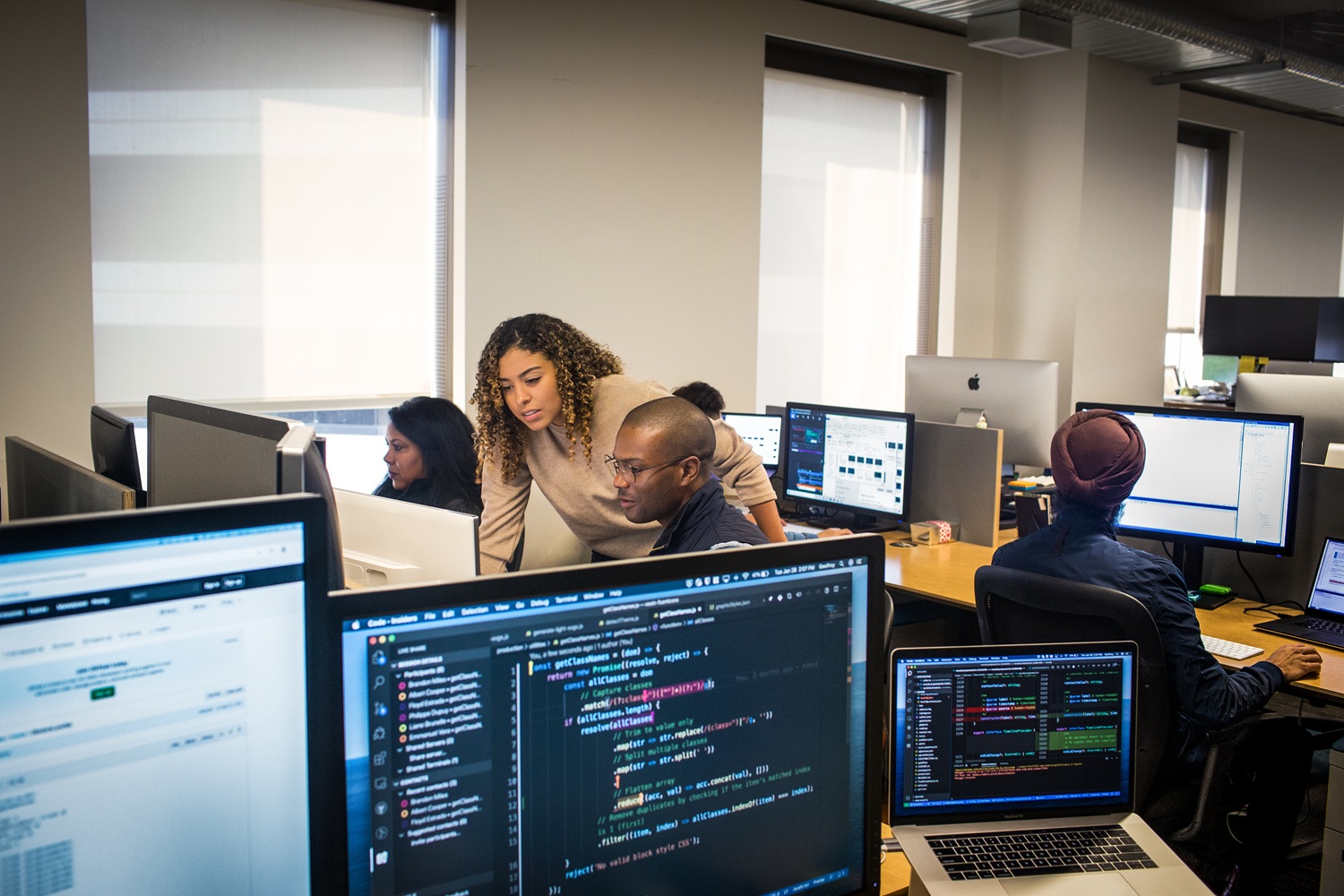 A team of workers sit at their computers collaborating.