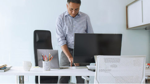 Чоловік, стоячи на столі під час введення тексту на клавіатурі комп'ютера