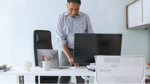 A man standing at a desk while typing on a computer keyboard