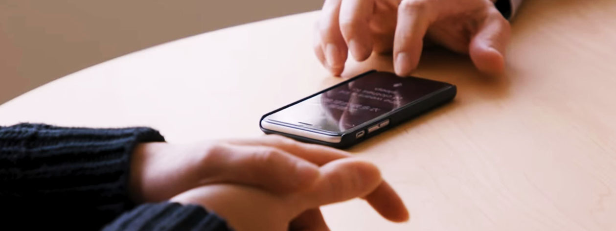 A parent's hand and teacher's hand using a single mobile device with the Translator conversation feature