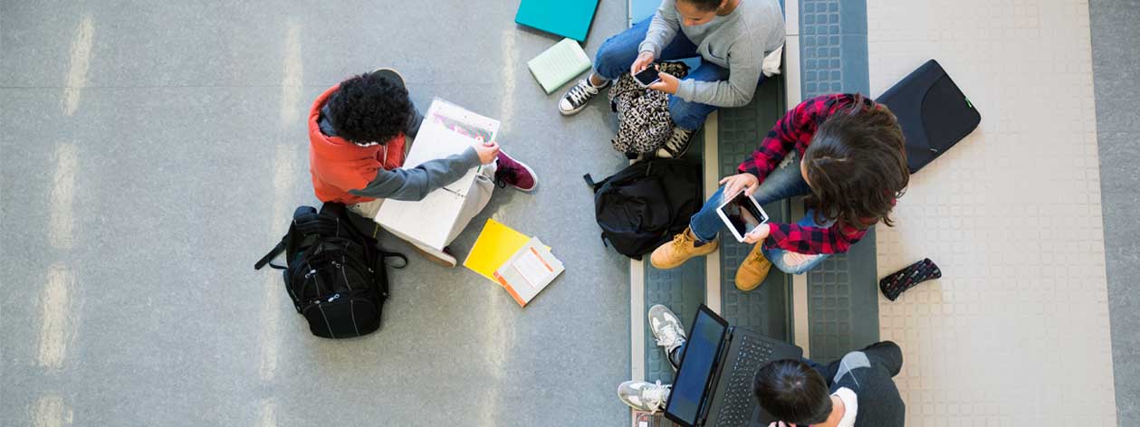 Czterej studenci siedzący przy stole studiujący i rozmawiający