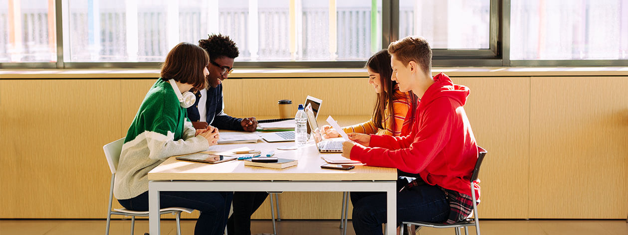 Quatre étudiants s’asseyant à une table étudiant et parlant