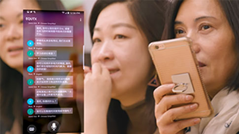 Translatorのマルチデバイス会話機能を使って携帯電話に話しかけているアジア人女性