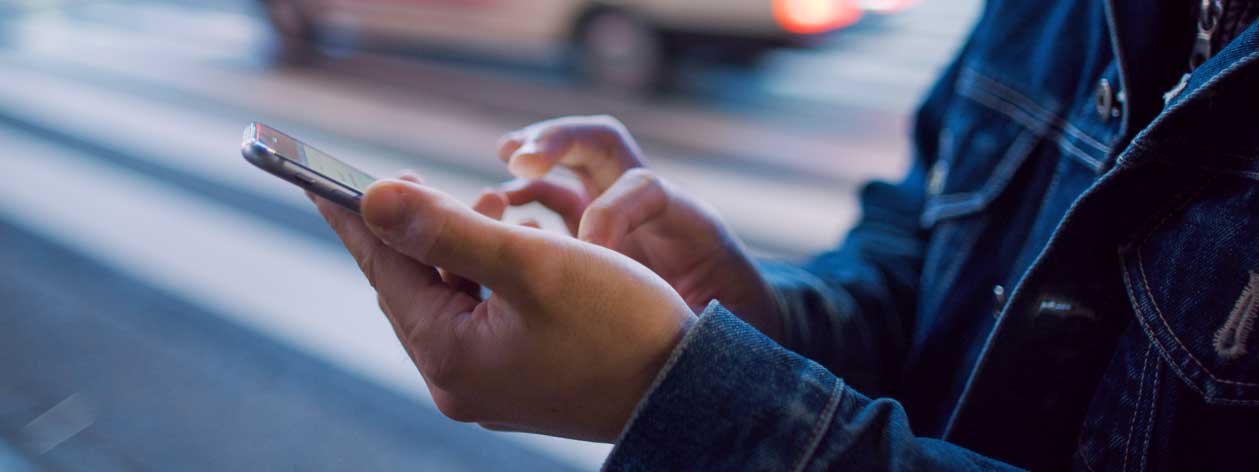 Mulher que prende um telefone com tráfego no fundo