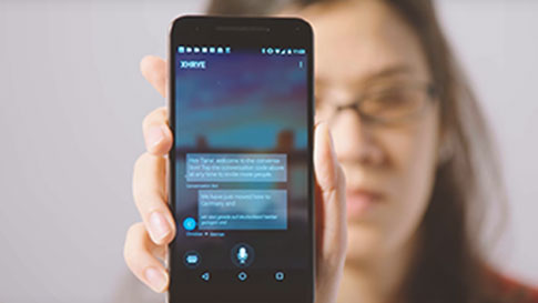 En kvinna som håller upp sin smarta telefon, som visar Translator-appen i konversations läge