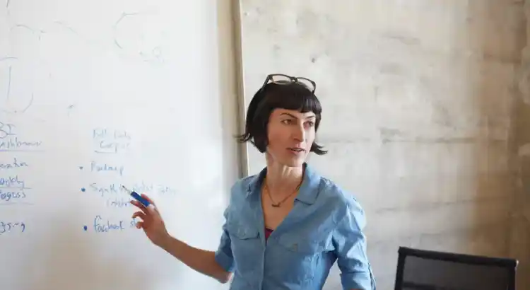 A picture of a woman standing infront of a whiteboard