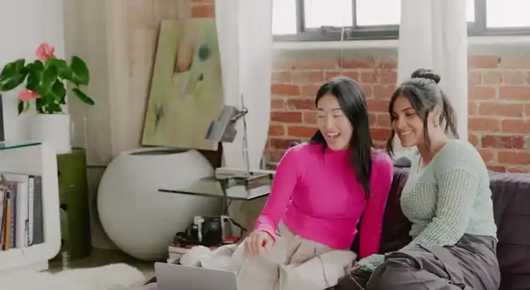 Two people sitting on a couch in a stylish living room, collaborating on a laptop.