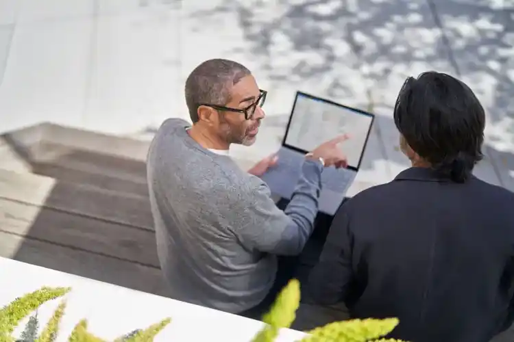 A picture of two people discussing with a laptop in their hand