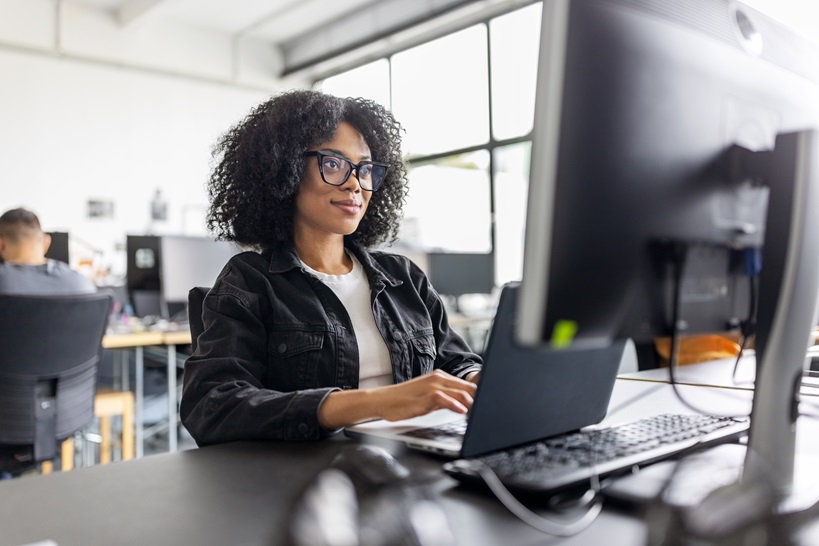 A woman works on a computer in an office, highlighting Microsoft's commitment to providing accessible and inclusive technology for all employees, promoting a diverse and equitable workplace.