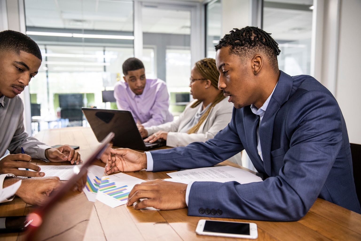 A group of Black professionals is in a meeting, reviewing documents and data. It represents teamwork, data analysis, and strategic planning