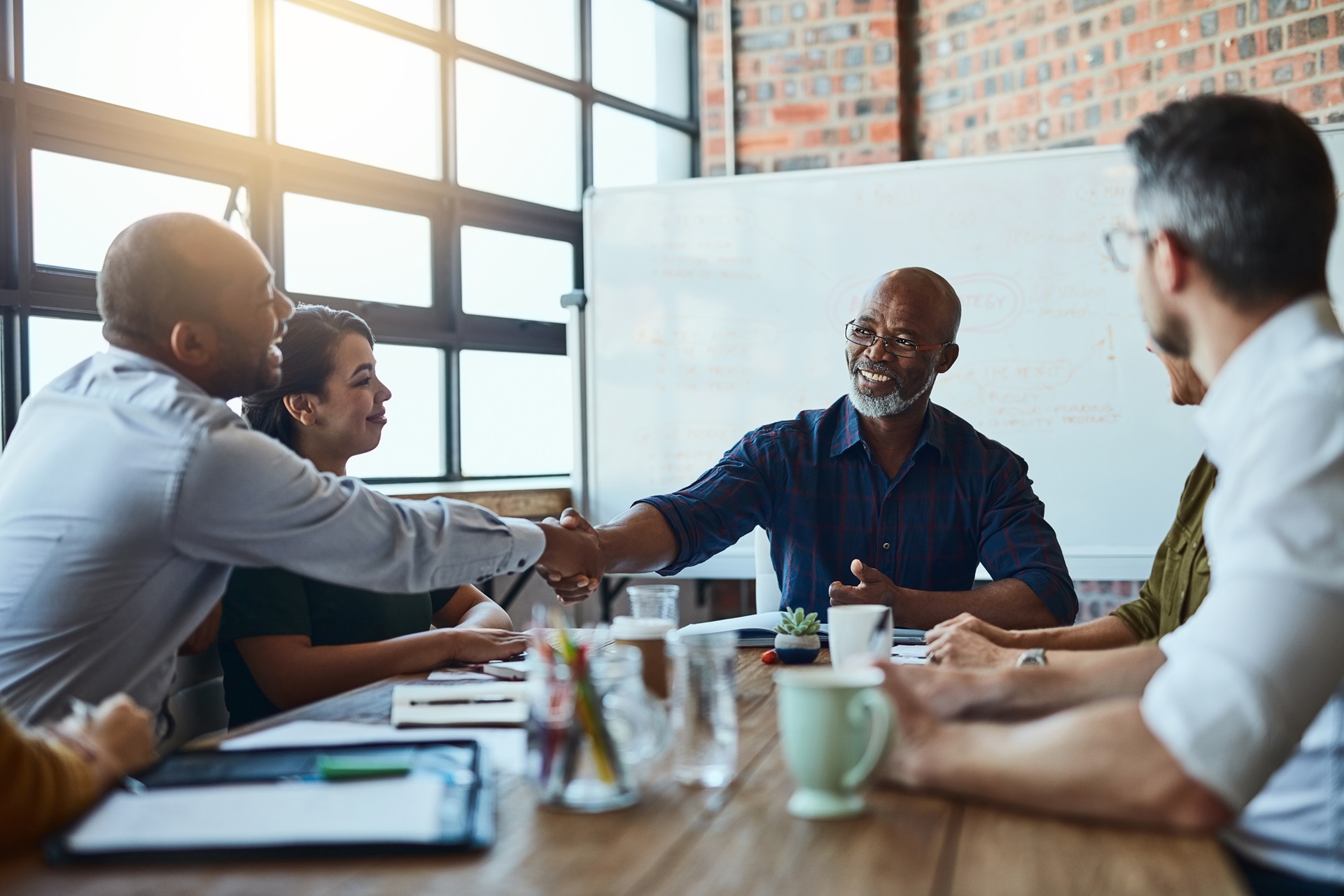 A diverse group of professionals in a modern office setting, sealing a business deal with a handshake. The scene emphasizes collaboration and inclusivity in a sustainable business environment.
