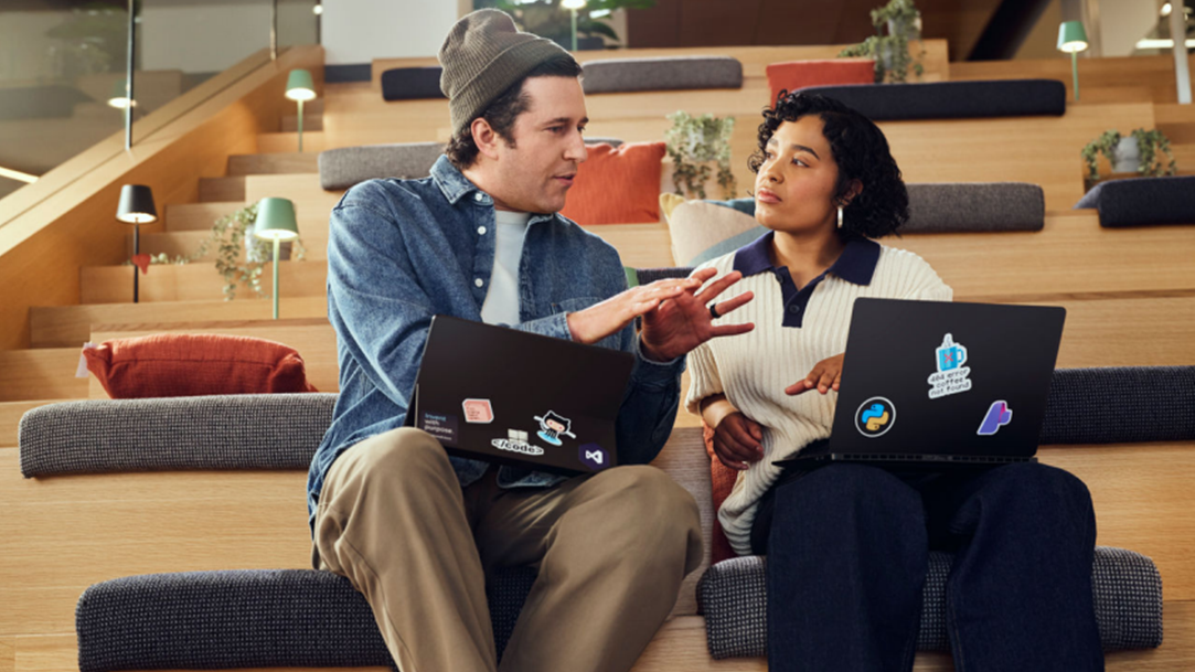 A person displays a laptop covered in stickers