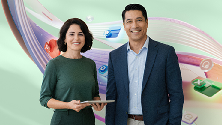 A woman in a green top holding a tablet and a man in a blue suit are standing next to each other smiling.